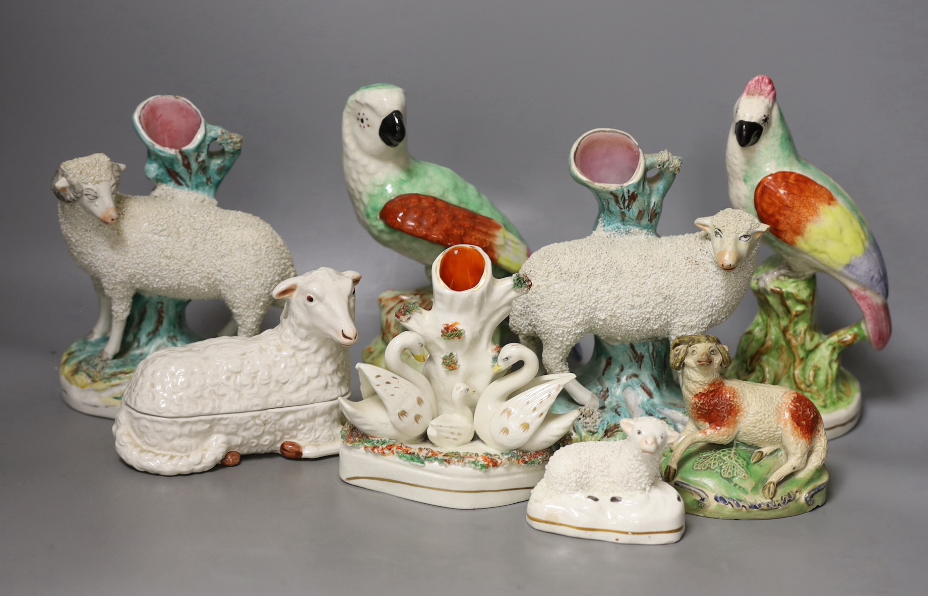 A group of Staffordshire animal and bird figures, to include a pair of sheep spill vases, two parrots, a swan spill vase, two further sheep and a cow and a continental pottery sheep tureen and cover - tallest 21.5cm